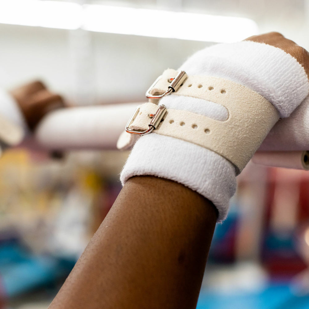 
                  
                    Load image into Gallery viewer, Reisport® Women&amp;#39;s Uneven Bar Grips - Double Buckle on hands holding uneven bars
                  
                